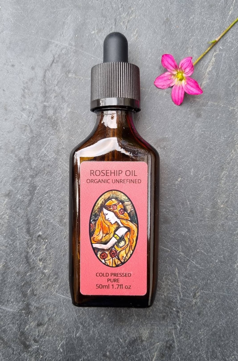 May include: A brown glass bottle with a dropper top filled with rosehip oil. The label reads "Rosehip Oil Organic Unrefined Cold Pressed Pure 50ml 1.7fl oz".