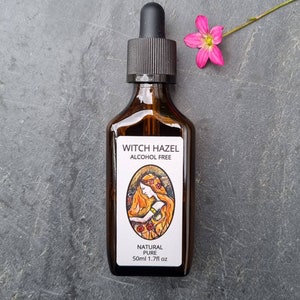 May include: A brown glass bottle with a dropper top and a white label. The label says "Witch Hazel Alcohol Free" and features a drawing of a woman with long red hair. The label also says "Natural Pure" and "50ml 1.7fl oz".