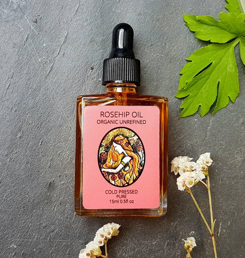 May include: A glass bottle of rosehip oil with a black dropper. The bottle is labeled "Rosehip Oil Organic Unrefined Cold Pressed Pure 15ml 0.5 fl oz".
