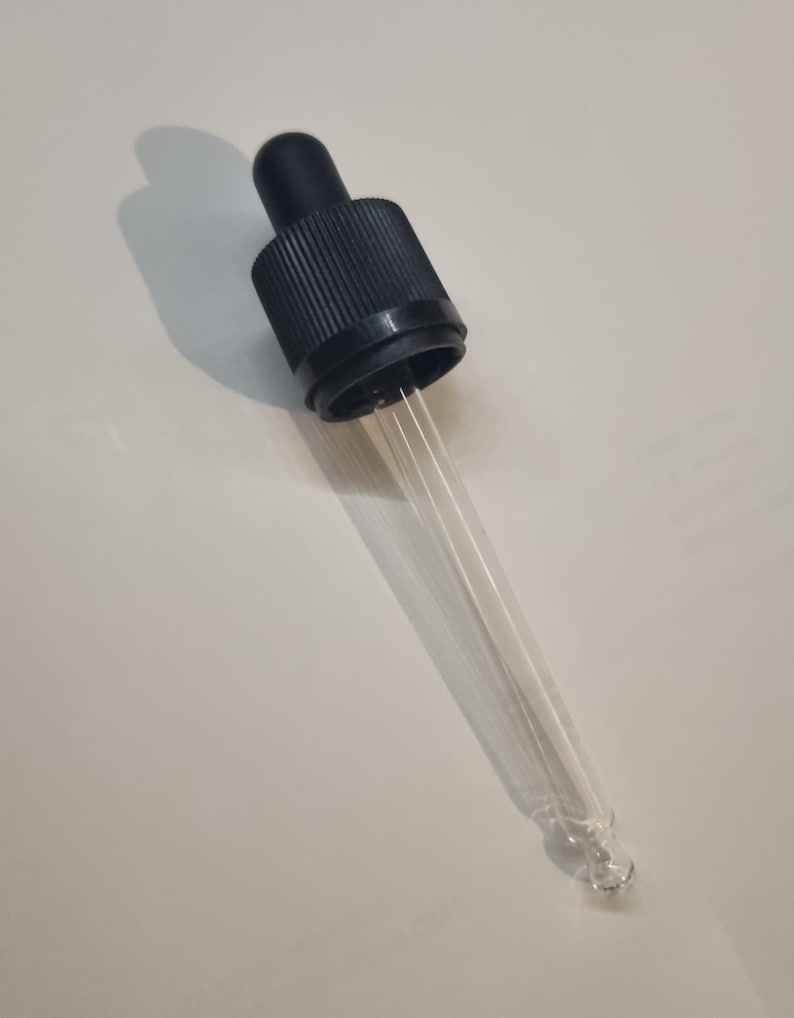 May include: A clear glass dropper with a black plastic cap. The dropper has a long, thin tube and a bulb at the end.
