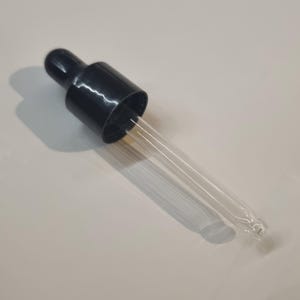 May include: A black plastic dropper bottle with a clear glass dropper. The dropper is long and thin with a pointed tip.