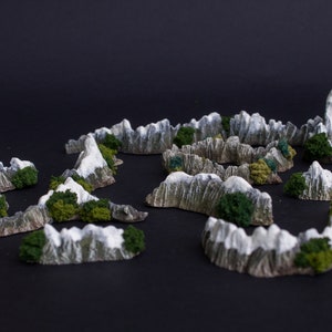 May include: A set of miniature mountain terrain pieces for tabletop gaming. The pieces are made of a light gray material with a textured surface and are painted with white snow and green foliage.