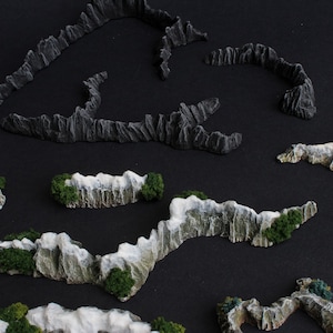 May include: A set of five miniature mountain ranges made of gray and white painted foam. The mountains are arranged in a curved pattern on a black background.