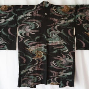 May include: Black kimono with a swirling abstract pattern in shades of teal, pink, and gold. The kimono has long sleeves and a mandarin collar. A small, decorative button is at the neckline. The garment is displayed against a white background.