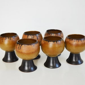 Pode incluir: Conjunto de seis taças de cerâmica marrom e preto com um design de esmalte de gotejamento.