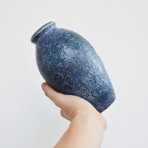 May include: A blue and green ceramic vase with a textured surface. The vase is hand-crafted and has a unique, organic shape.