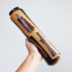 May include: A black and brown ceramic vase with a geometric pattern. The vase is cylindrical and has a slightly flared opening.