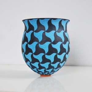 May include: A blue and black ceramic vase with a geometric pattern. The vase is round and has a wide opening.
