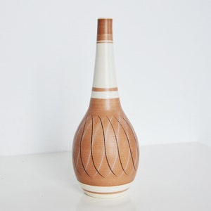 May include: A brown ceramic vase with a white stripe around the top and bottom. The vase has a unique design of carved lines that create a pattern of overlapping ovals.