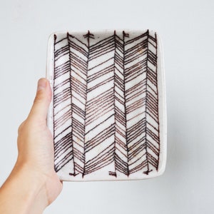 May include: A white ceramic rectangular dish with a brown chevron pattern.
