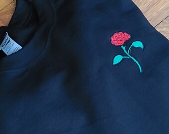 May include: Black sweatshirt with a red rose embroidered on the left chest.
