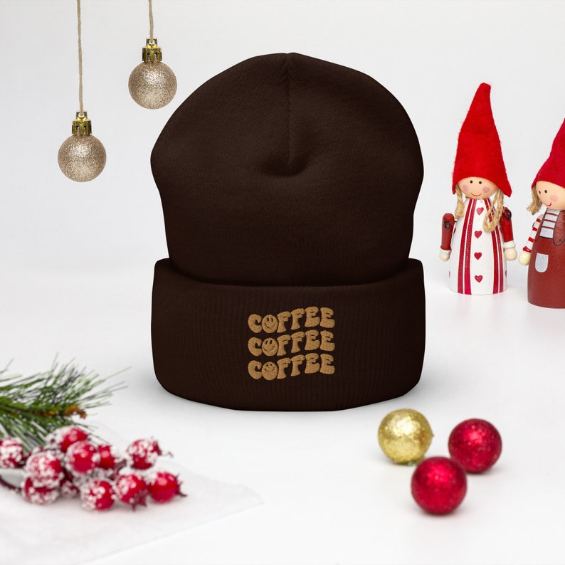 May include: Brown knit beanie with a fold-over cuff and the word "COFFEE" repeated three times in a brown and gold font.