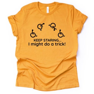 May include: A mustard yellow t-shirt with a black graphic of four wheelchair symbols and the text "KEEP STARING... I might do a trick!"