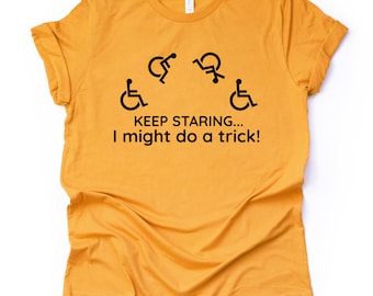 May include: A mustard yellow t-shirt with a black graphic of four wheelchair symbols and the text "KEEP STARING... I might do a trick!"