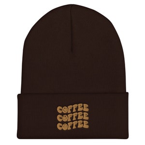 May include: Brown beanie with a brown embroidered design that says "COFFEE" three times with a smiley face in each word.