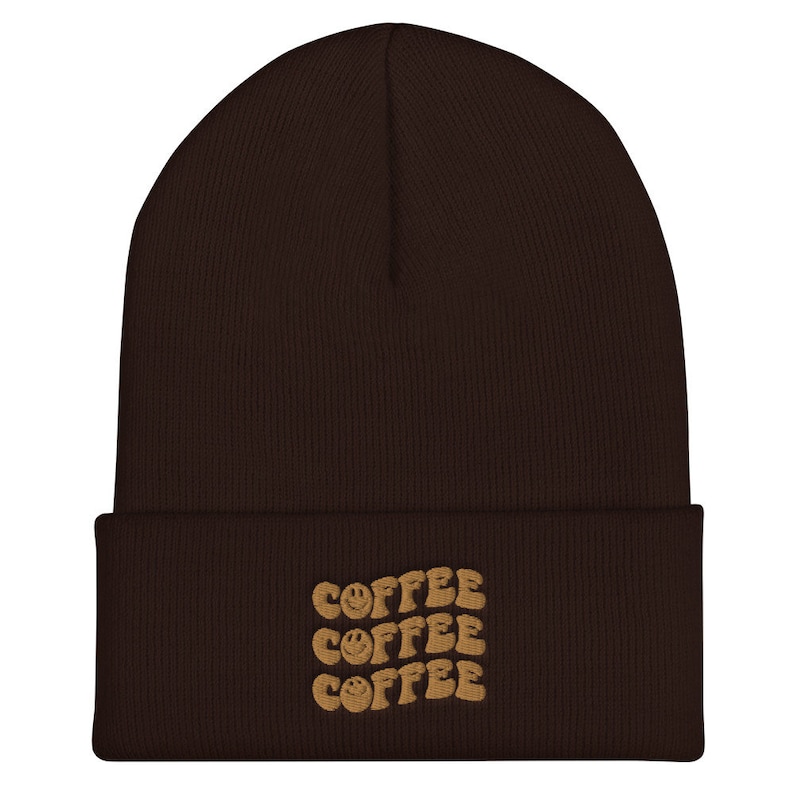 May include: Brown beanie with a brown embroidered design that says "COFFEE" three times with a smiley face in each word.