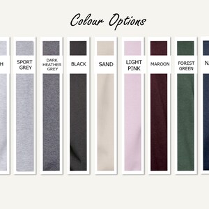 May include: Color options for a t-shirt, including white, ash, sport grey, dark heather grey, black, sand, light pink, maroon, forest green, navy, and light blue.