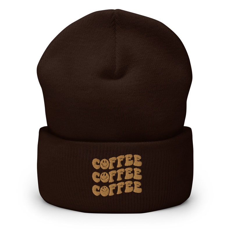 May include: A brown beanie with a fold-over cuff and the word "COFFEE" repeated three times in a brown font with a smiley face in each word.