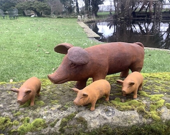 May include: A family of rustic, brown-toned pig sculptures. The large pig is flanked by three smaller piglets, all with detailed features. The sculptures are displayed on a mossy stone surface, creating a charming outdoor decor scene.