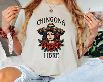 May include: A beige t-shirt with a graphic print of a woman wearing a sombrero and roses. The text "CHINGONA LIBRE" is printed below the graphic.