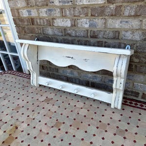 May include: A white ceramic mug with a black handle and the text "But First, Coffee" in a bold, black font. The mug is set against a blurred background, suggesting a cozy setting.