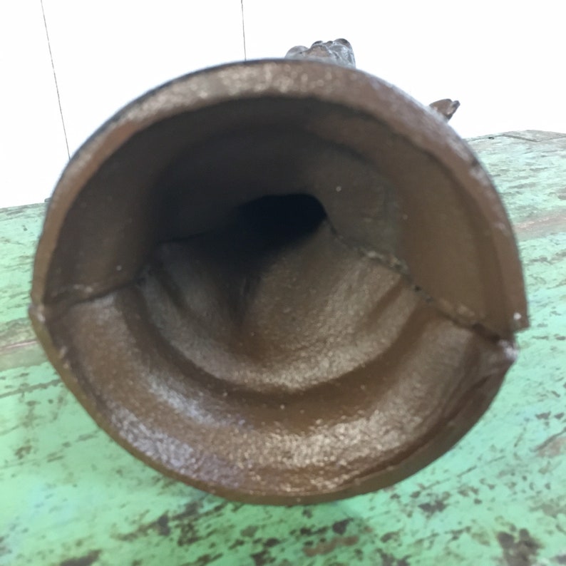 May include: A brown cast iron statue of a hand with the fingers extended. The statue is hollow and has a hole in the bottom.