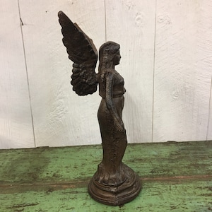 May include: A cast iron angel statue with wings outstretched, standing on a pedestal. The statue is painted in a dark brown color.
