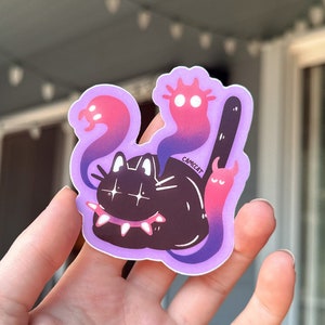 May include: A black cat with a spiked collar and glowing eyes is surrounded by three pink and purple ghosts. The ghosts have large eyes and are in various shapes. The sticker is on a purple background and has the word "CAMCAT" written on it.