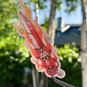 May include: A pink and red cartoon sword with flames, stars, and a heart charm. The sword is on a white background.