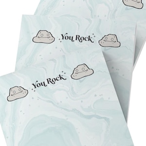 May include: Three blue and white marble notepad sets with a cartoon rock face and the text "You Rock" on each page.