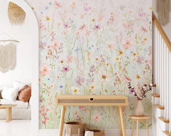 Peut inclure: Une peinture murale représentant une prairie à l'aquarelle avec des fleurs sauvages roses, jaunes et violettes et des papillons. Une console en bois clair avec un tiroir en cannage est placée devant le mur, avec deux paniers tressés.
