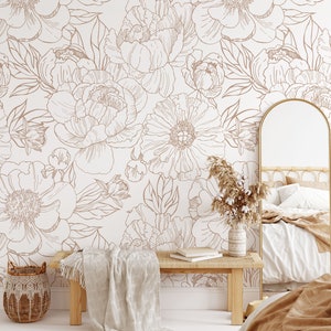 Puede incluir: Un interior de dormitorio con una pared blanca con un patr&oacute;n de papel tapiz floral en marr&oacute;n. El papel tapiz tiene un patr&oacute;n repetitivo de grandes peon&iacute;as y hojas. La habitaci&oacute;n cuenta con un banco de madera con una manta blanca, una cesta de mimbre, un espejo y una cama con una manta marr&oacute;n.
