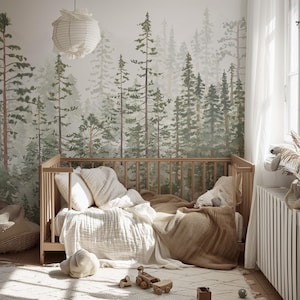 May include: A light wood crib with bedding, including pillows and a blanket, sits on a patterned rug. A forest mural is on the wall behind the crib. A paper lantern hangs from the ceiling. Wooden toys are on the rug.
