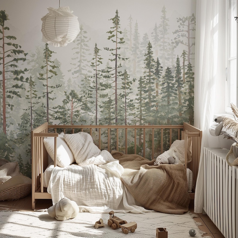 May include: A light wood crib with bedding, including pillows and a blanket, sits on a patterned rug. A forest mural is on the wall behind the crib. A paper lantern hangs from the ceiling. Wooden toys are on the rug.