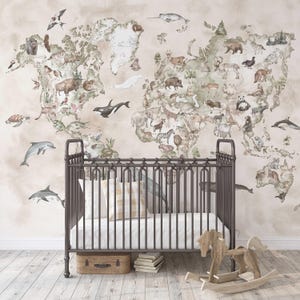 May include: A watercolor world map with animals from different continents. The map is printed on a light beige background. A crib with a white and brown patterned pillow is in the foreground.