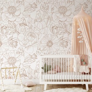 Puede incluir: Una cuna blanca con un dosel blanco y un papel tapiz floral con contornos marrones. La cuna tiene un colch&oacute;n blanco y una manta blanca con un patr&oacute;n de estrellas rosa y verde.