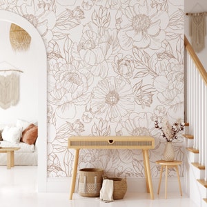 Puede incluir: Una pared blanca con un papel tapiz de patr&oacute;n floral marr&oacute;n. El papel tapiz presenta un patr&oacute;n repetitivo de grandes peon&iacute;as y hojas. Una mesa consola de madera con dos cestas tejidas se encuentra frente a la pared. Un peque&ntilde;o taburete de madera se encuentra a la derecha de la mesa.