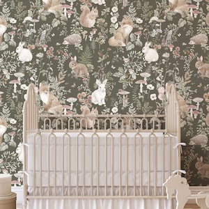 May include: A white crib with a green and brown woodland animal wallpaper featuring foxes, squirrels, rabbits, and mushrooms. The wallpaper has a vintage aesthetic.