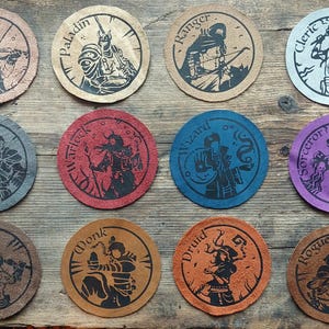 May include: A collection of twelve round leather coasters, each featuring a different fantasy class illustration and name. The coasters are in various colors, including brown, red, blue, and purple. The names include Bard, Paladin, Ranger, and Cleric.
