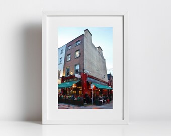 May include: A red brick building with a green awning and the text "J. Grogan" and "The Castle Bar" in Dublin, Ireland. People are sitting outside the bar on a patio.