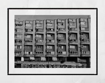May include: A black and white photograph of a large apartment building with multiple windows and balconies. The building has the words "ADMINISTRATIVA", "OSCILAMISS", "MONGE", and "KONGE" written on the facade.