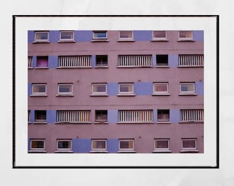 May include: A pink and blue building with many windows. The windows are arranged in a grid pattern. Some of the windows have blinds.