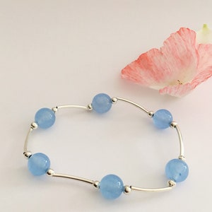 May include: A delicate bracelet with a silver chain and six light blue round beads.