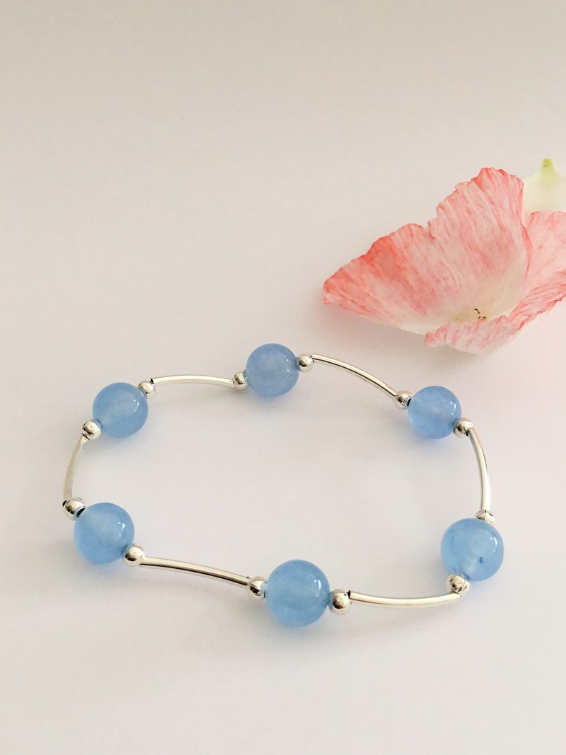 May include: A delicate bracelet with a silver chain and six light blue round beads.