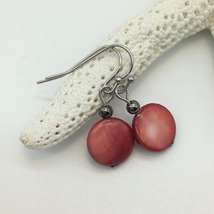 May include: A pair of earrings with red shell disc pendants and silver hooks.
