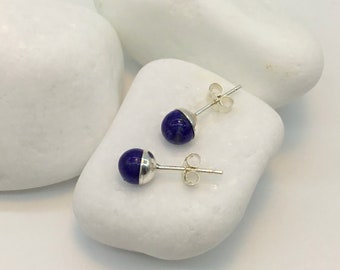 May include: A pair of silver stud earrings with round blue lapis lazuli stones.