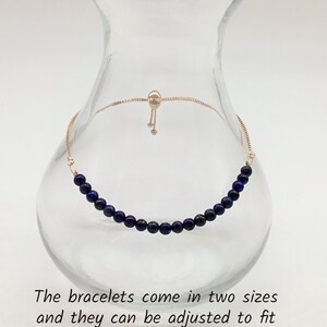 May include: A delicate bracelet made with dark blue lapis lazuli beads and a gold chain with a sliding clasp. The bracelet is adjustable to fit most wrist sizes.