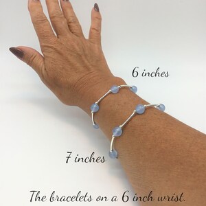 May include: Two silver bracelets with light blue beads on a 6 inch wrist. The bracelets are 6 inches and 7 inches long.