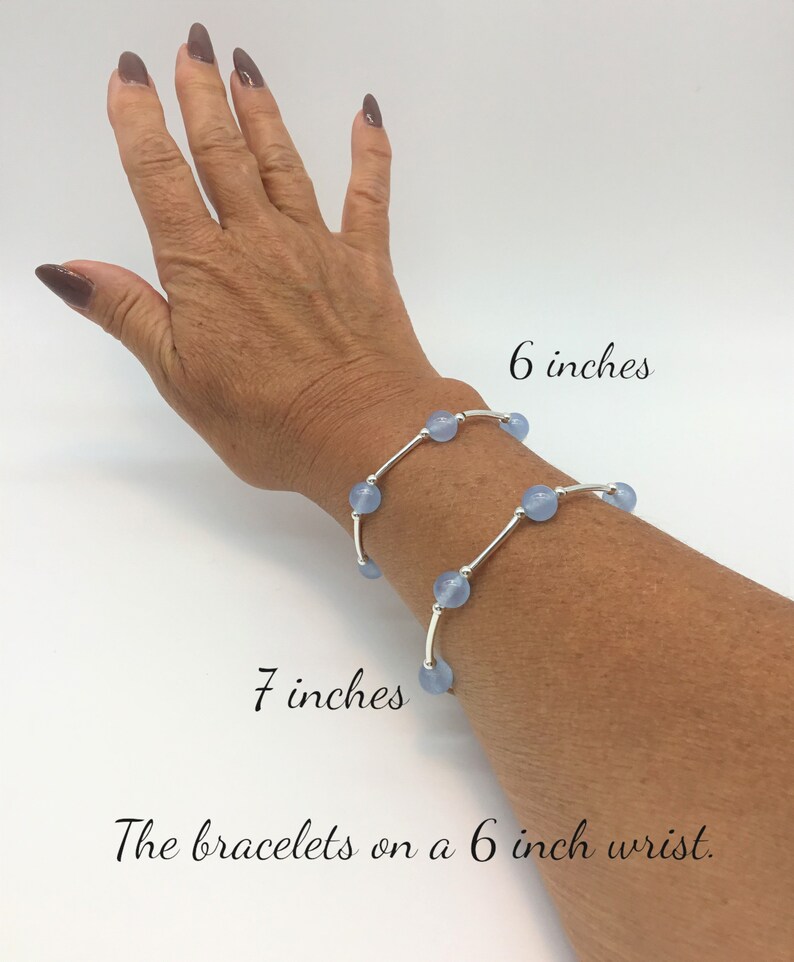 May include: Two silver bracelets with light blue beads on a 6 inch wrist. The bracelets are 6 inches and 7 inches long.
