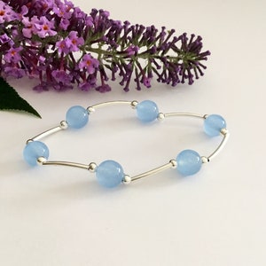 May include: A delicate bracelet with a silver chain and light blue gemstone beads.
